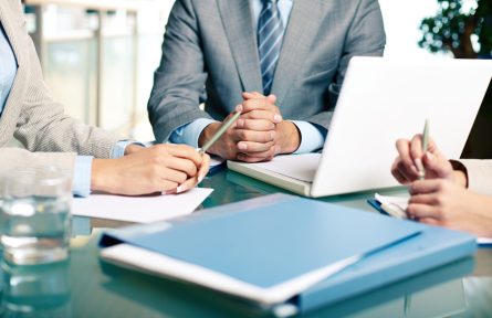 Close-up of hands of boss at workplace with laptop and hands of two females near by