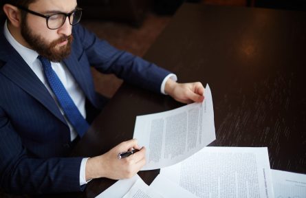 Image of serious businessman signing contract at workplace